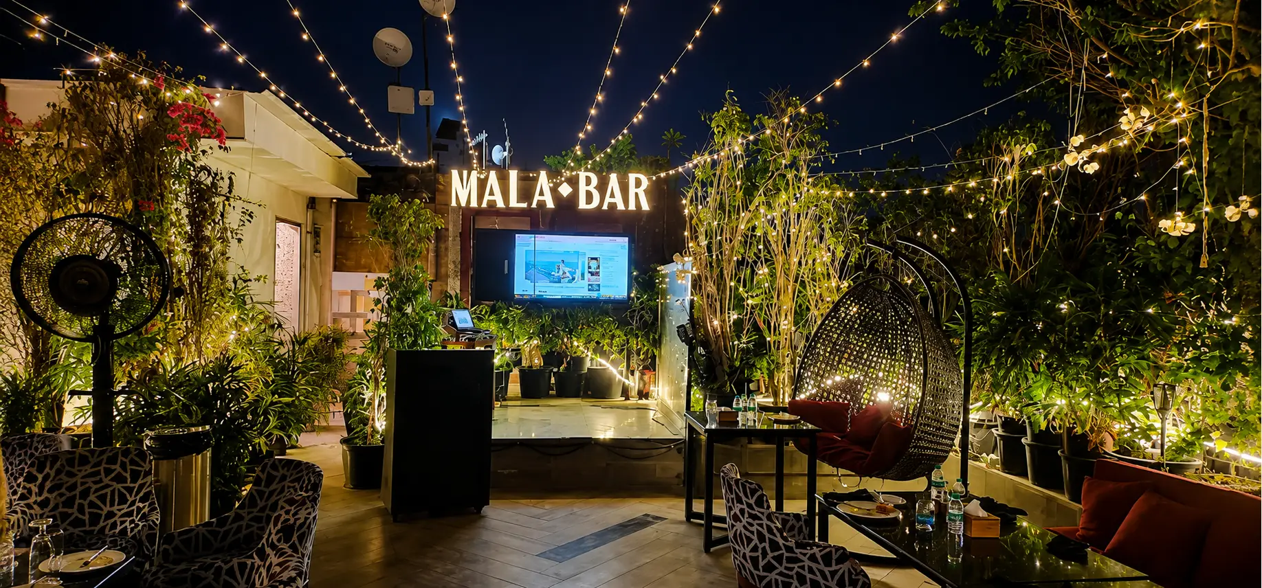 Outdoor seating area with festive lighting at Mala Akbari
